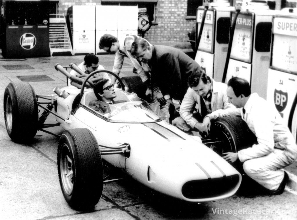 Masten Gregory sits in the cockpit of the 1965 BRP Indycar as team manager Tony Robinson looks on. 