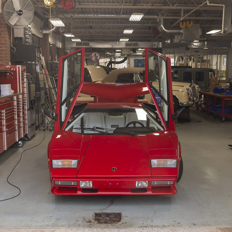 Red sports car with vertical doors raised in Ai Design shop